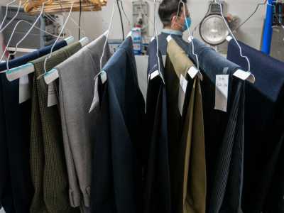 Giuseppe ci conduce poi nella parte retrostante colma di grucce con su poggiati pantaloni...